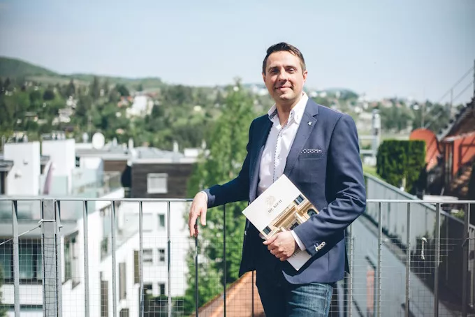 Christoph Koch, Geschäftsführer von Koch Immobilien, mit Exposé auf einer Dachterrasse – Ihr Immobilienmakler in Wien